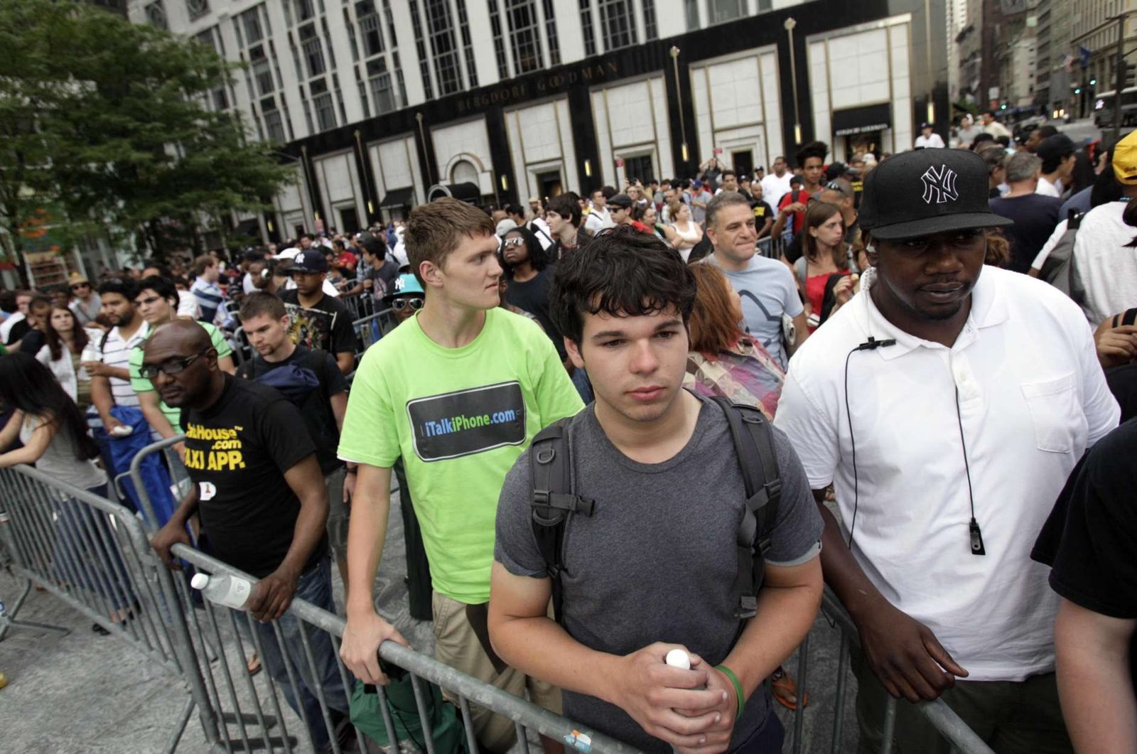 A long line behind barricades outside the Fifth Avenue Apple Store, with a friend in a bright green iTalkiPhone dot com shirt